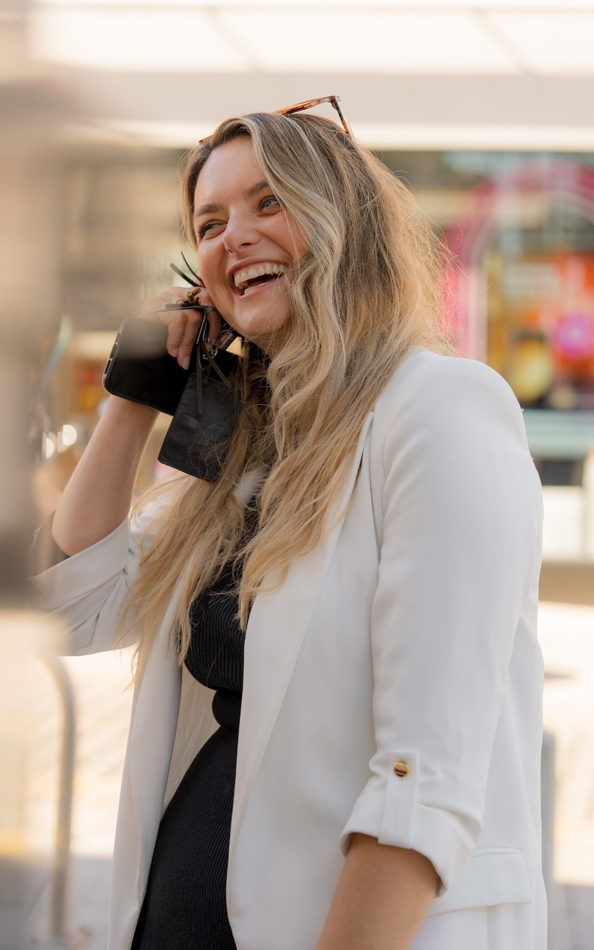 A woman smiling while holding her phone and wallet