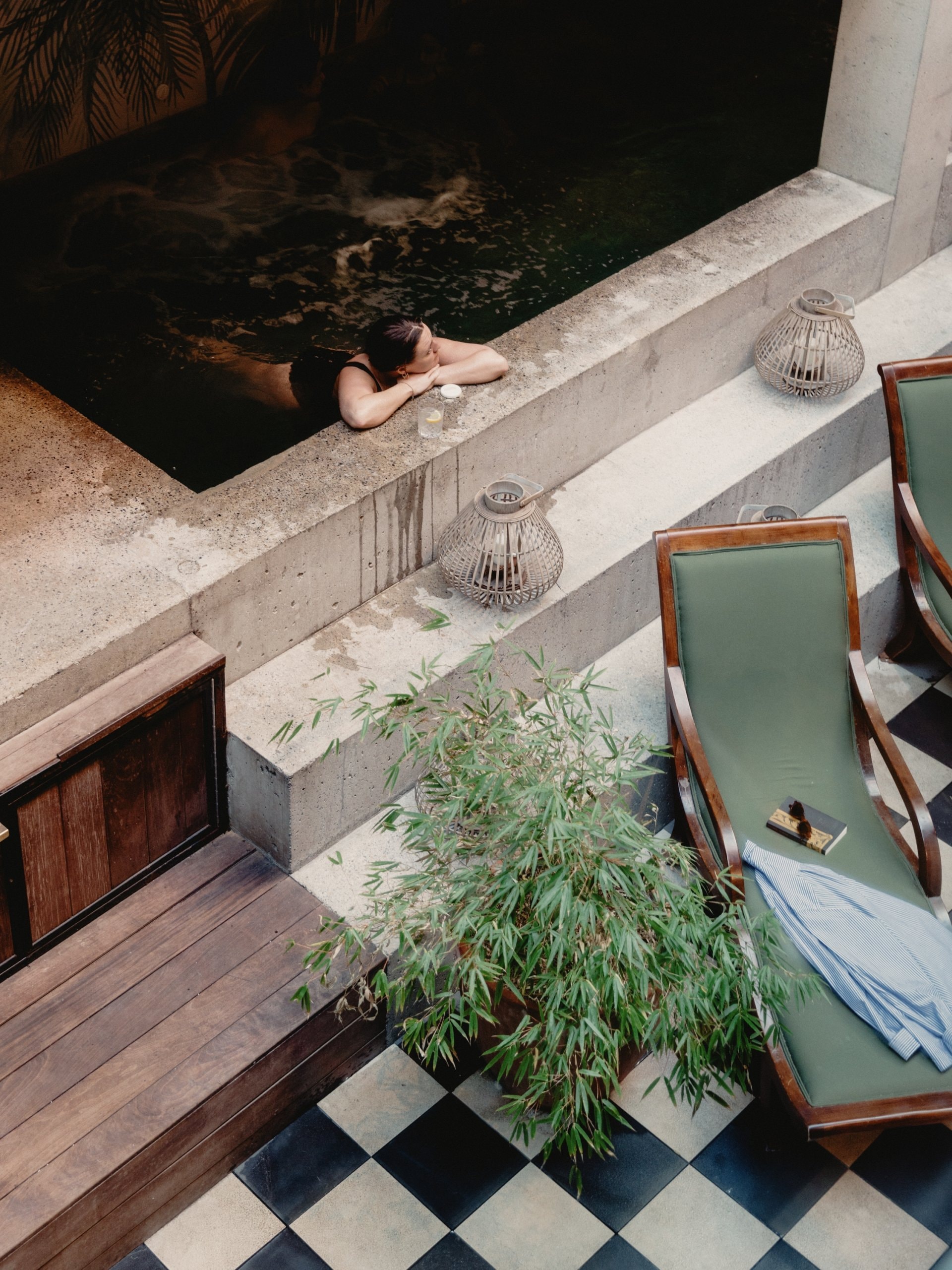 Woman relaxing in pool next to lounge chairs