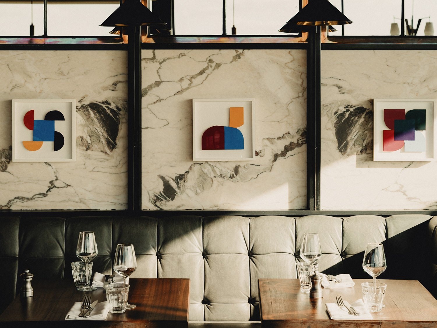Paintings on a wall behind booth seating in a dining area